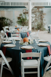 Round Wedding Reception Table with Blue Linen and Red Napkins and Pumpkin Centerpiece | Fall Halloween Inspired Reception Decor Ideas