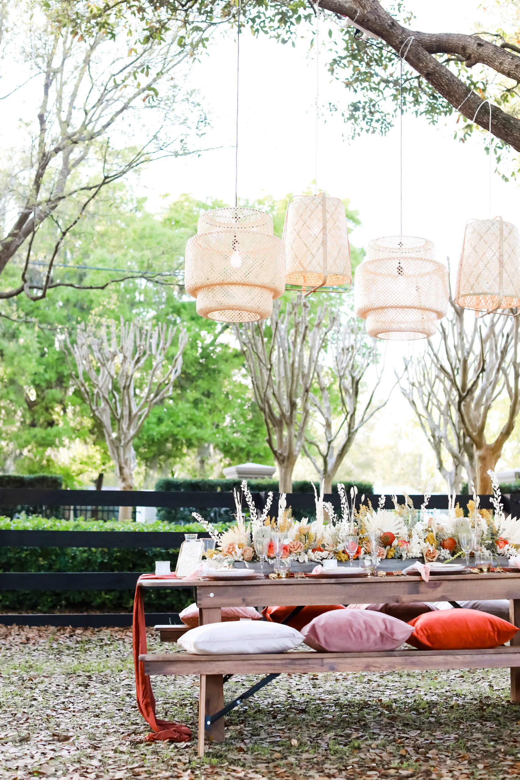 Boho Styled Wicker Lanterns Outdoor Wedding Decor Inspiration Boho Picnic with and Fall Reception Tablescape with Wooden Farm Table and Benches with Pillow Centerpiece Inspiration | Tampa Bay Rentals Gabro Event Services