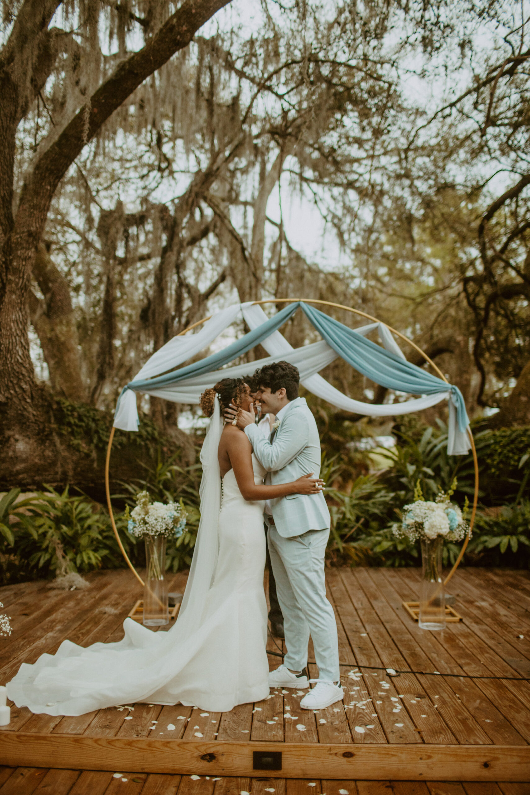 Bride and Groom First Kiss Wedding Portrait | The Broken Oak Outdoor Wedding Ceremony | Round Gold Circle Metal Arch With Blue and White Drapery | Tampa Bay Venue Mill Pond Estate