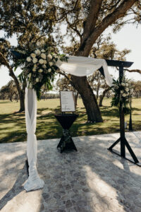 Black Wedding Arch with White Organza Draping and White Roses and Greenery Wedding Ceremony Inspiration | Dade City Wedding Venue Simpson Lakes
