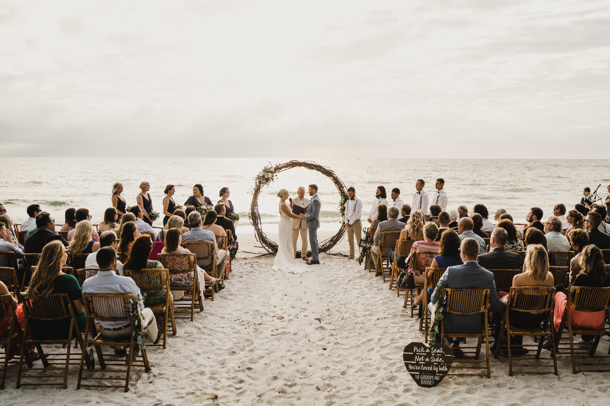 Rustic Beach Wedding Inspiration with Circular Wooden Arch | Folding Rattan Chair Seating Ideas | Round Wedding Arch | Tampa Bay Rental Gabro Event Services | Treasure Island Photographer Videographer J&S Media | Planner Kelci Leigh Events | Florist Monarch Events & Design