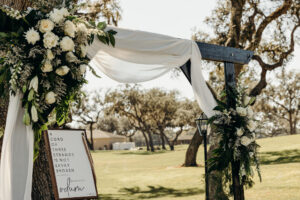 Black Wedding Arch with White Organza Draping and White Roses and Greenery Wedding Ceremony Inspiration