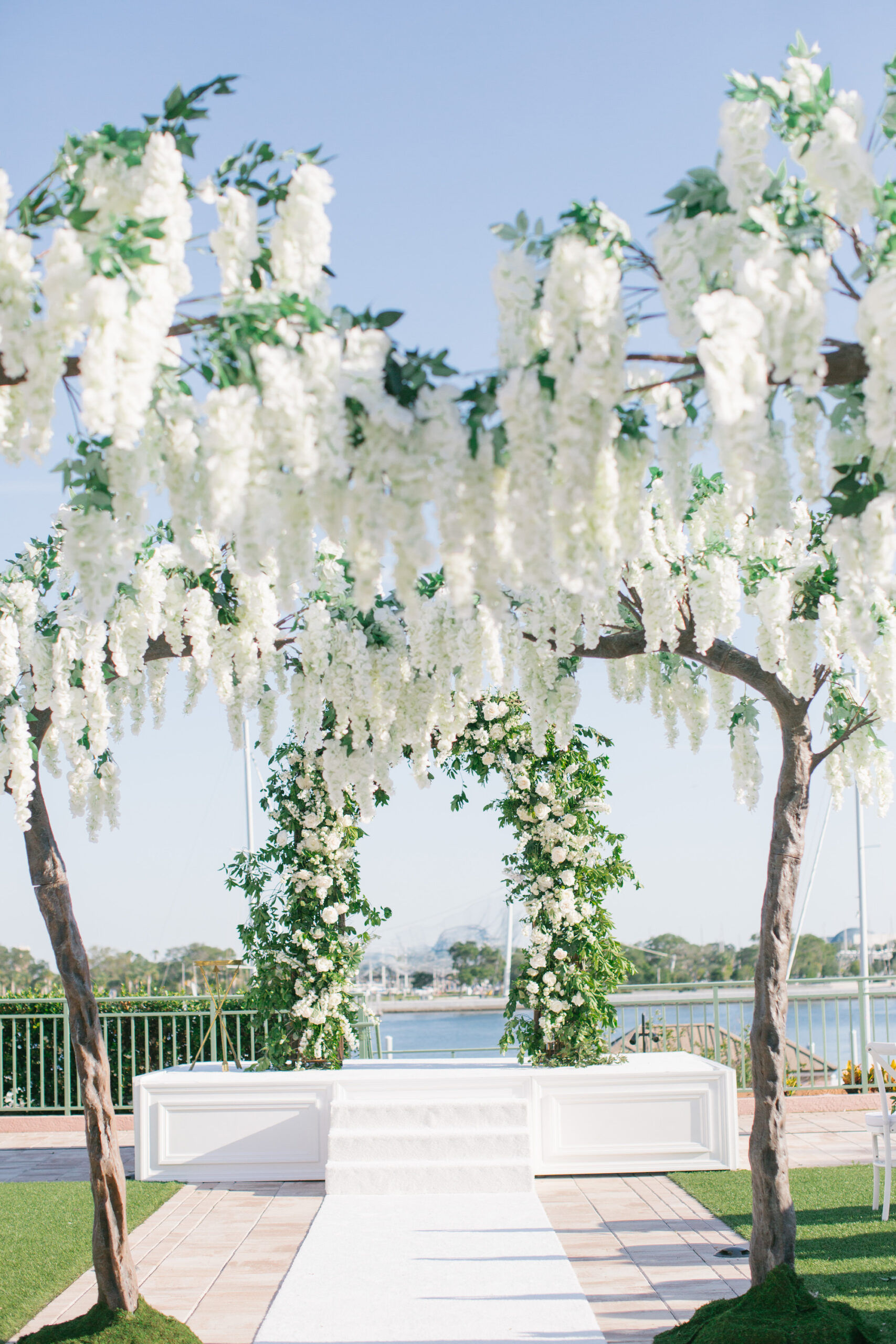 Tall Wisteria Tree Wedding Aisle Decor | Whimsical White and Greenery Garden Floral Wedding Arch with White Aisle Runner\