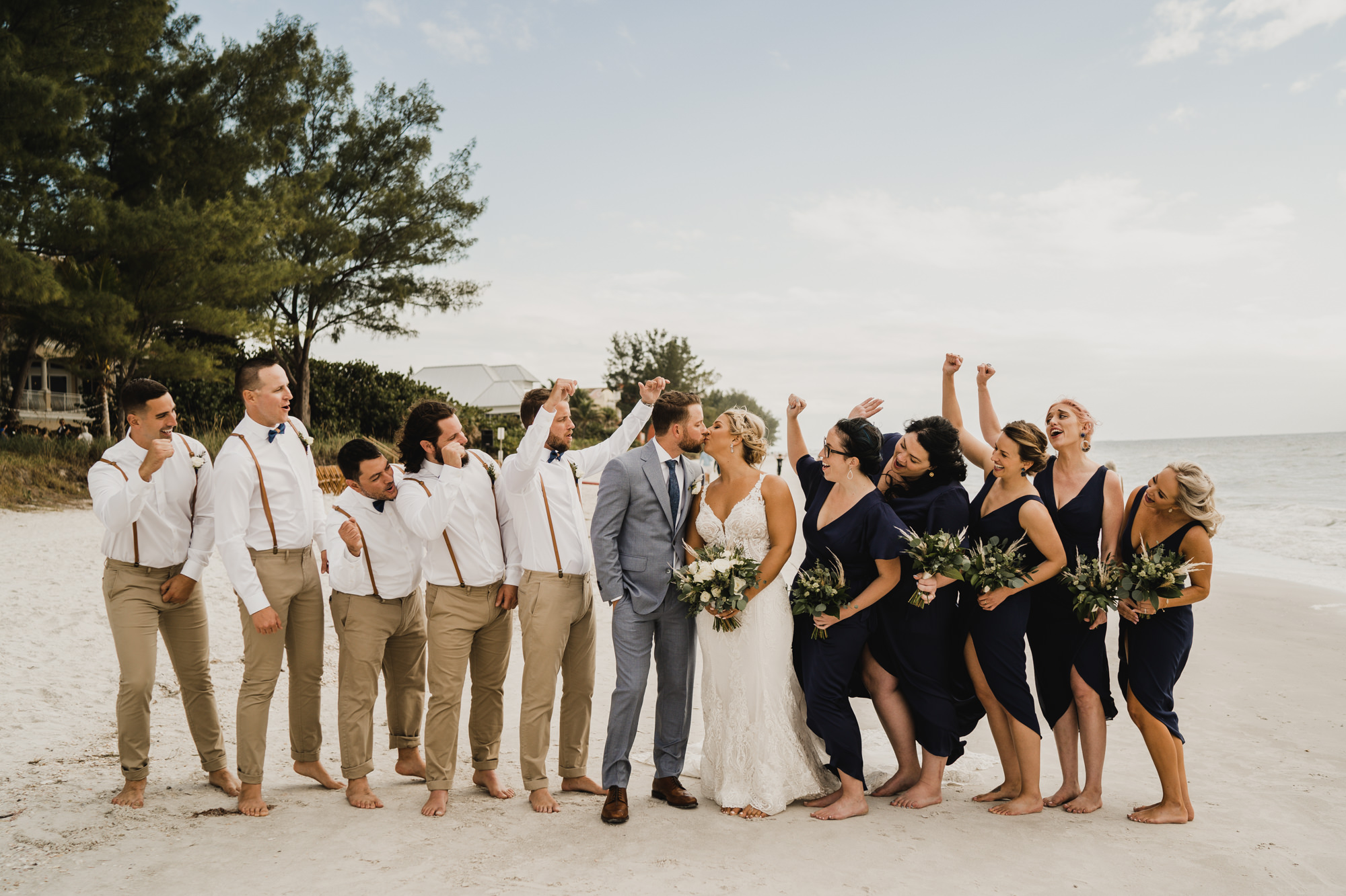 Rustic Wedding Party Attire Inspiration | Groomsmen Suspenders and Khaki Pants | Bridesmaids Navy Dress | Gray Groom Suit with Navy Tie | Barefoot Beach Wedding