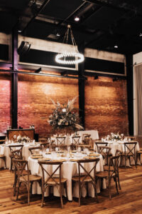 Elegant Boho Wedding Inspiration | Wooden Crossback Chairs | White Linen | Tall Flower Stand with Eucalyptus, Fern, Pampas Grass, Roses Centerpieces | Modern Industrial Exposed Brick Venue Ideas