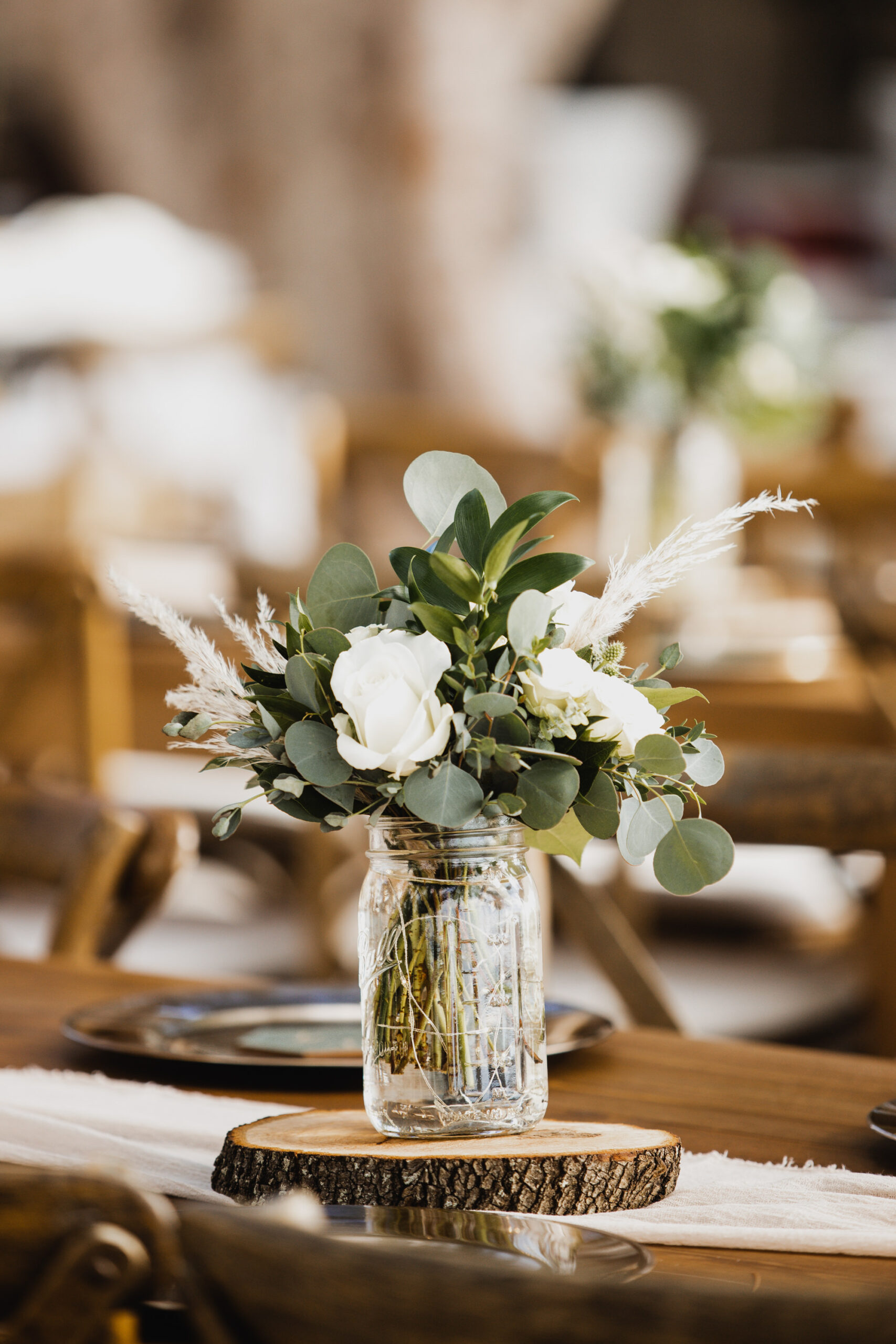 Mason Jar Vase with White Roses, Pampas Grass, Eucalyptus on Wood Slice Centerpiece Ideas | Treasure Island Florist Monarch Events and Design
