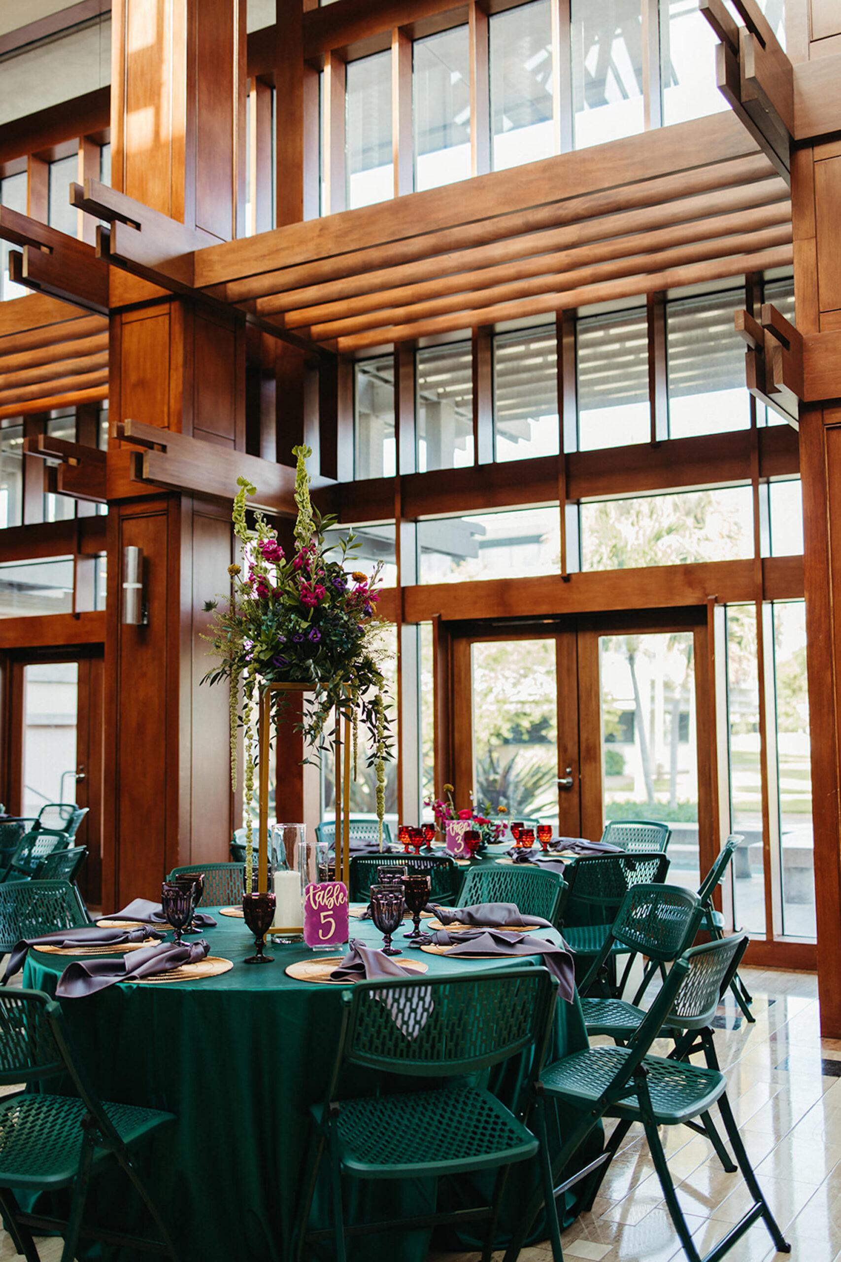 Tall Gold Flower Stand | Green Folding Chair Seating Inspiration | Dark Wood Wedding Reception | Fuchsia and Gold Acrylic Table Numbers | Tampa Bay Venue Poynter Institute