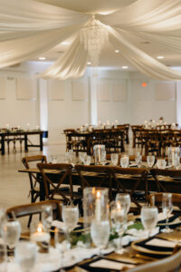 Indoor Wedding Reception with Crossback Chairs, Wooden Feasting Tables, and White Draping | Tampa Bay Venue Simpson Lakes