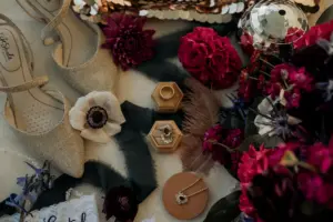 Dark and Moody Wedding Flat Lay Inspiration with Anemones and Red Floral Details Jewelry in Butterscotch Velvet Ring Boxes