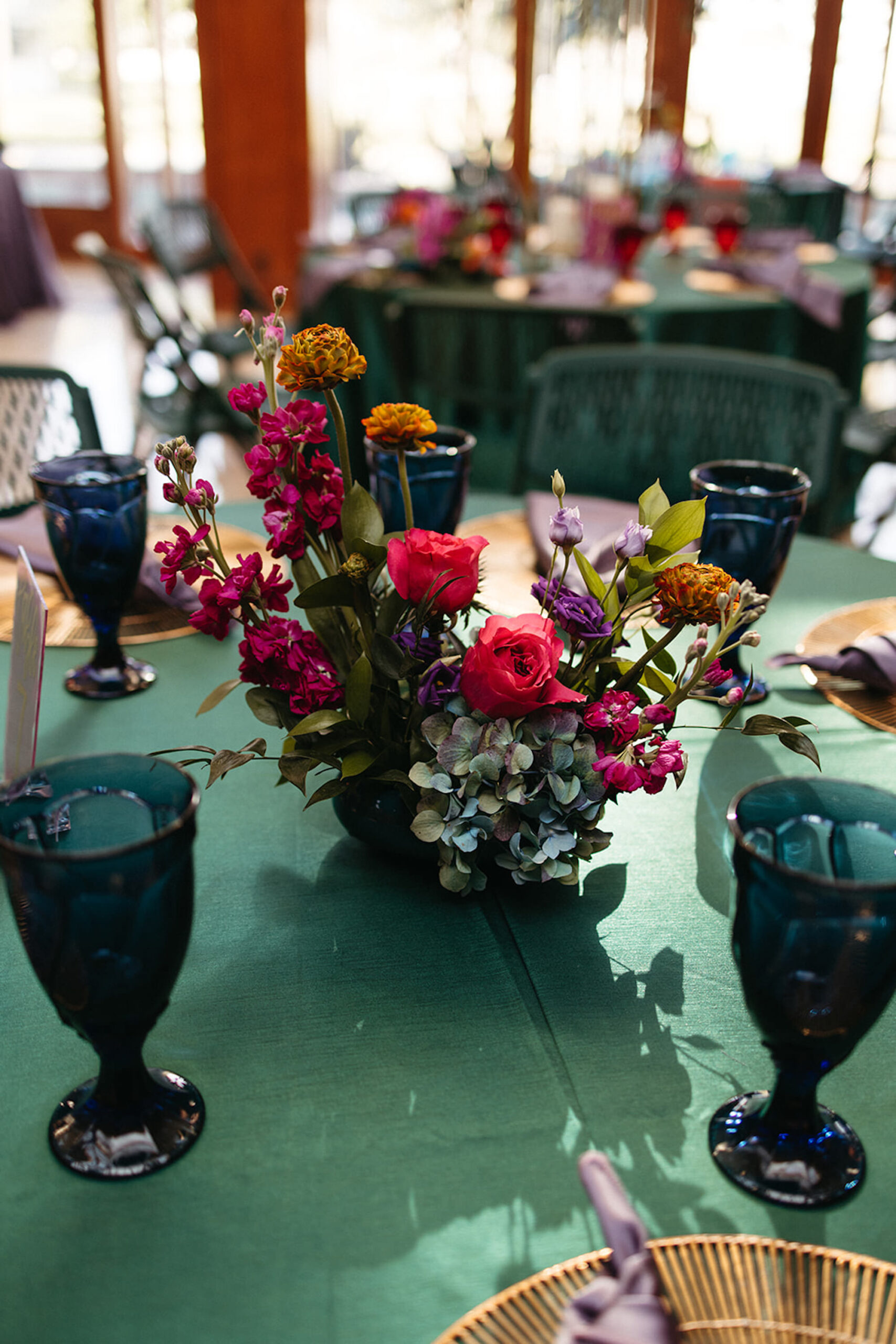Vibrant Pink, Fuchsia, Orange, and Violet Floral Centerpieces | Dark Green Goblet Glassware and Green Linen Tableware Wedding Reception Ideas