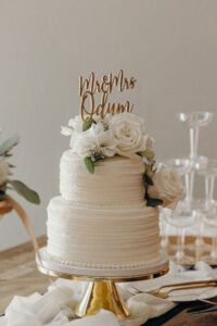 Two Tier Classic Round White Wedding Cake with Rose Detailing and Gold Cake Topper
