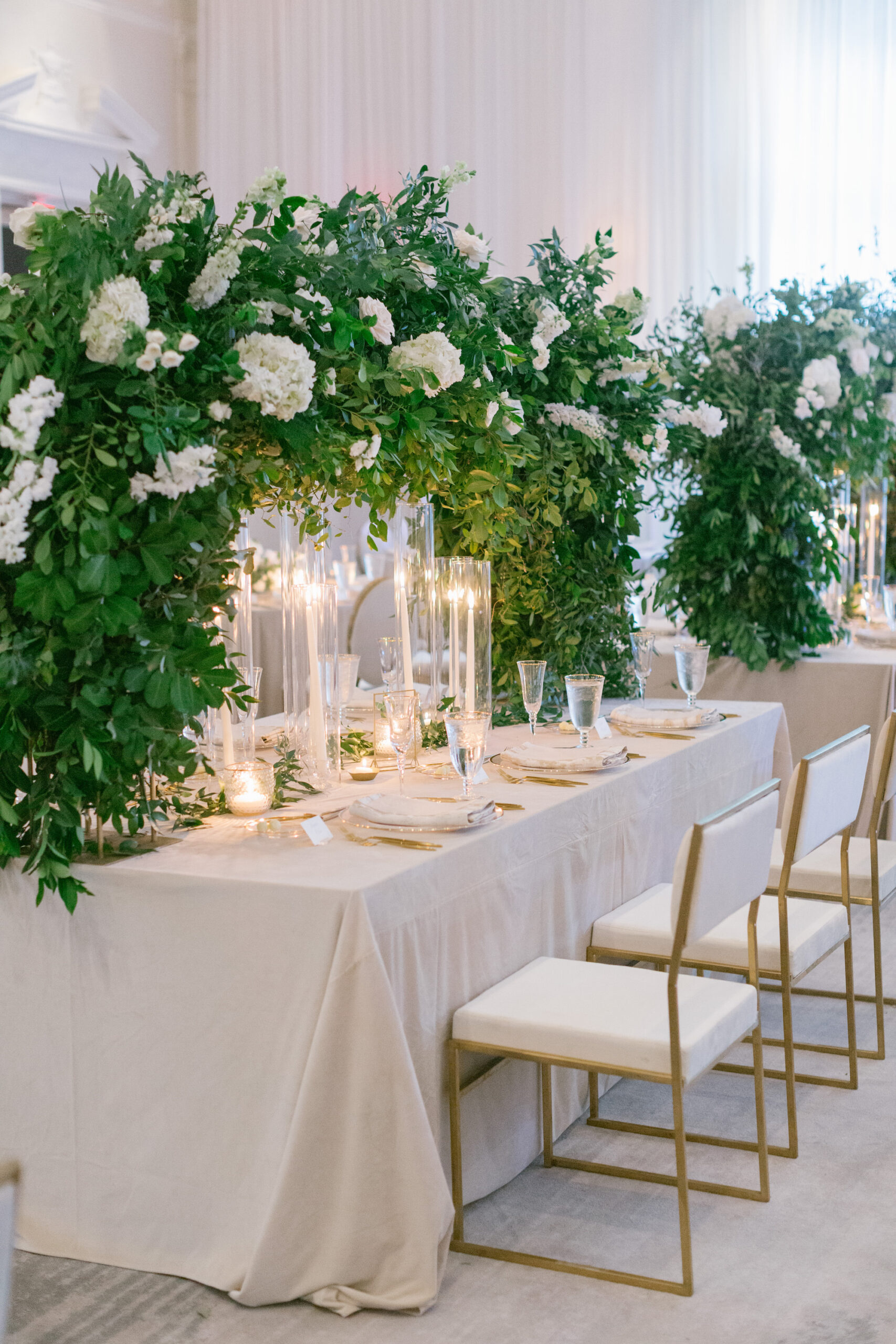 Luxurious Ballroom Wedding Reception Ideas | Modern White and Gold Chair Satin Inspiration | Tabletop Arch White Flowers with Greenery Centerpiece Inspiration | Hurricane Taper Candle Holders | Tampa Bay Rental A Chair Affair | Over the Top Linen Rental