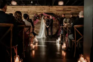 Bride and Groom Exchange Vows in Dark and Moody Wedding Ceremony with Wooden Crossback Chairs and Pillar Candle Decor Ideas | Madeira Beach Venue The West Events