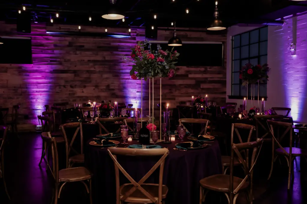 Dark and Moody Wedding Reception Ideas with Purple Uplighting, Tall Gold and Floral Centerpieces and Wooden Crossback Chairs | Madeira Beach Venue The West Events