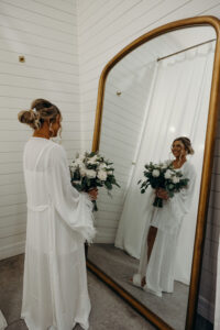 Bride Wedding Portrait Getting Ready in White Robe with White Rose Bouquet and Greenery