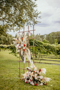 Boho Garden Trellis Flower Arrangements with Palm Fronds, Pampas Grass, Roses, and Greenery Altar Decor Inspiration | Tampa Bay Florist Save the Date Florida