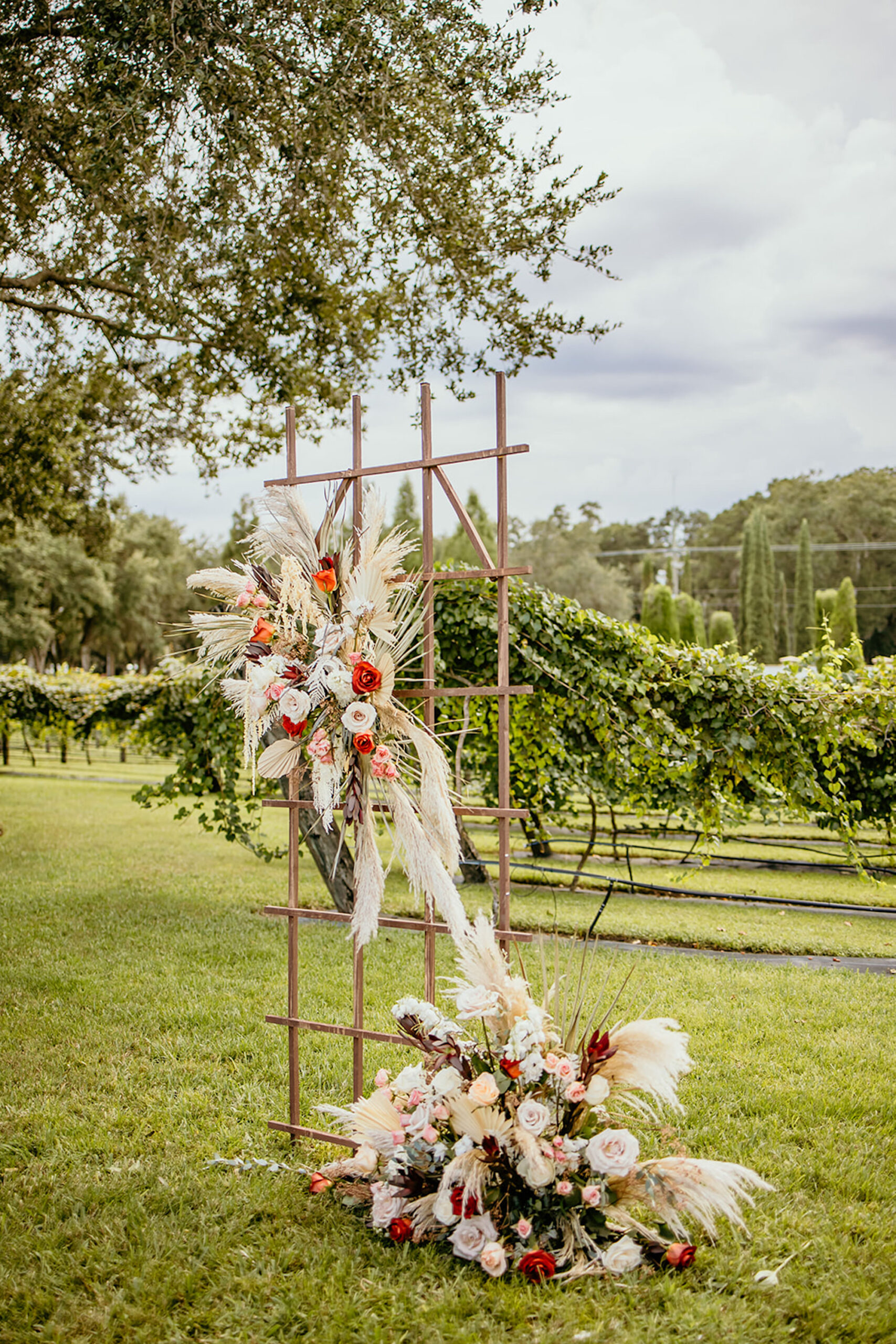 Boho Garden Trellis Flower Arrangements with Palm Fronds, Pampas Grass, Roses, and Greenery Altar Decor Inspiration | Tampa Bay Florist Save the Date Florida