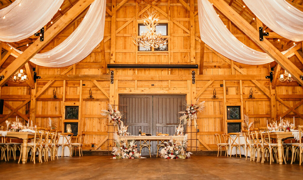 Boho Sweetheart Table Flower Inspiration | Fern, Pampas Grass, Palm Leaves, Eucalyptus, and Roses Floor and Backdrop Floral Arrangements | White Drapery | Market Lights | Rustic Wooden Crossback Chair Seating Inspiration | Tampa Bay Wedding Venue Mision Lago Estate | Gabro Event Rentals | Florist Save the Date Florida