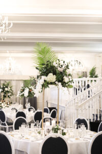 Black and White Reception Chairs Inspiration | Tall Tropical Greenery Wedding Centerpieces with Gold Stands