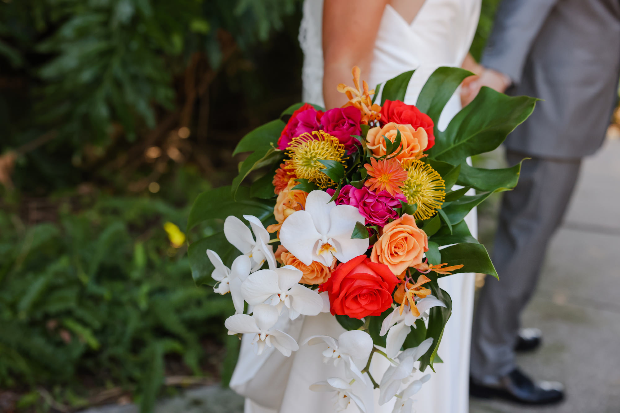 Tropical White Orchid, Yellow Pincushion Protea, Red and Orange Roses, Monstera Bridal Wedding Bouquet