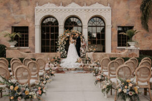 Wedding Ceremony at Italian Style Mansion with Garden Ombre Rainbow Floral Ceremony Arch and Rustic Boho Wooden Chairs | Decor Inspiration | Central Florida Venue Howey Mansion