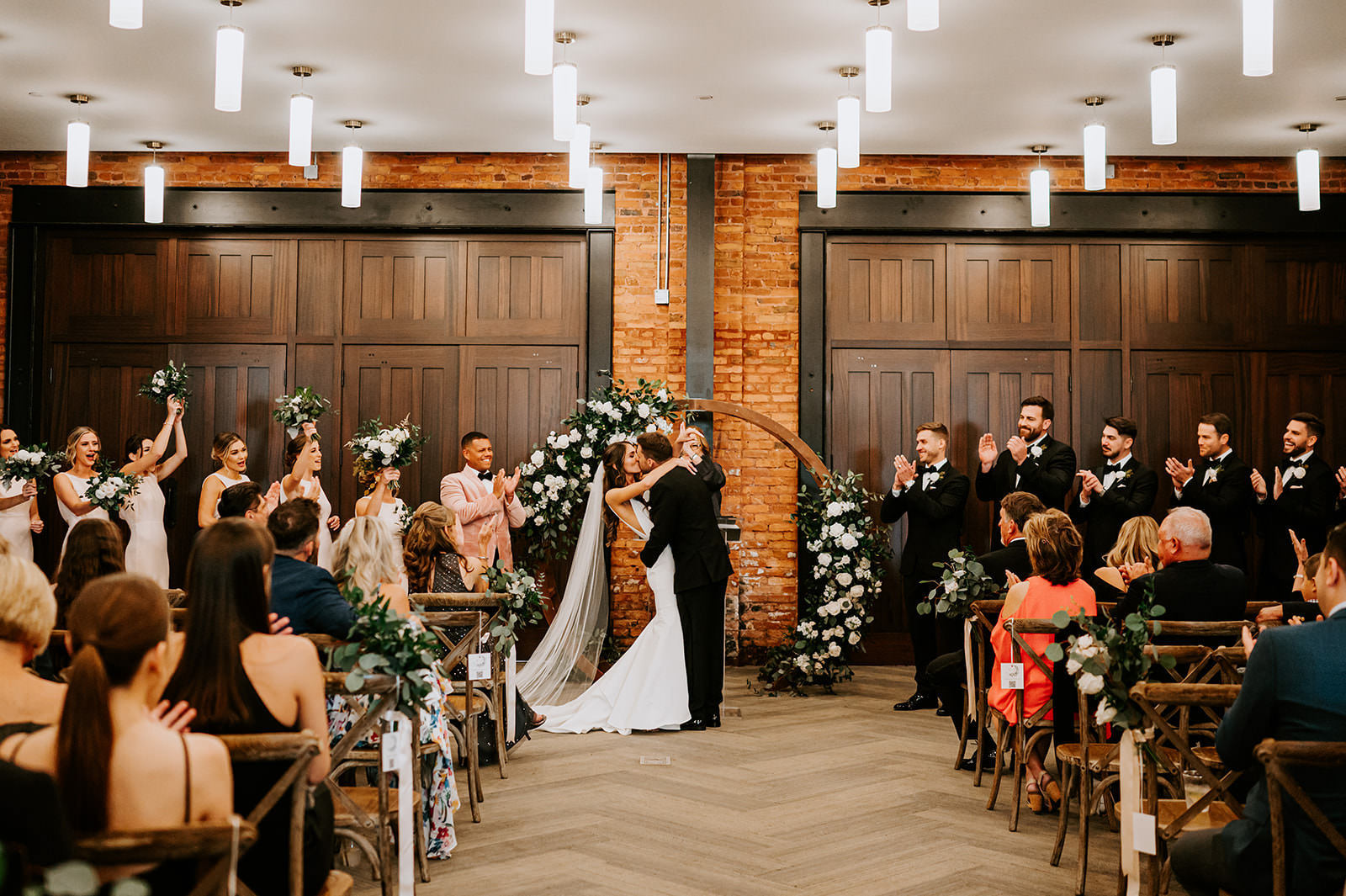 Bride and Groom First Kiss Wedding Portrait | Round Wooden Wedding Arch Ideas | Classic White Rose and Greenery Flower Arrangement Inspiration