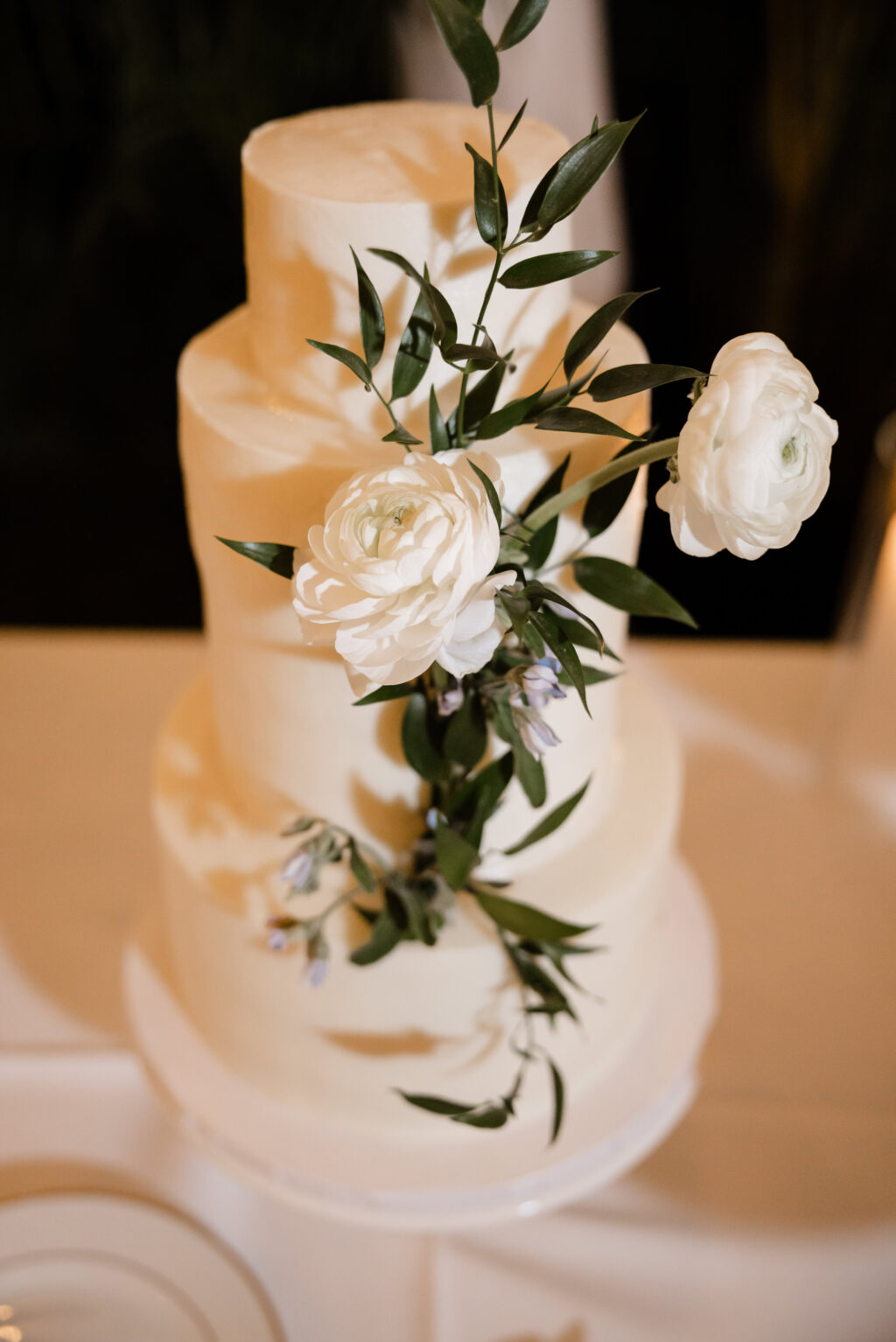 Three-Tiered Round White Wedding Cake with White Garden Roses and Ruscus Greenery