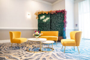 Yellow Lounge Furniture with Boxwood Wall and Neon Sign Wedding Reception Seating Inspiration | Clearwater Rentals Gabro Event Services