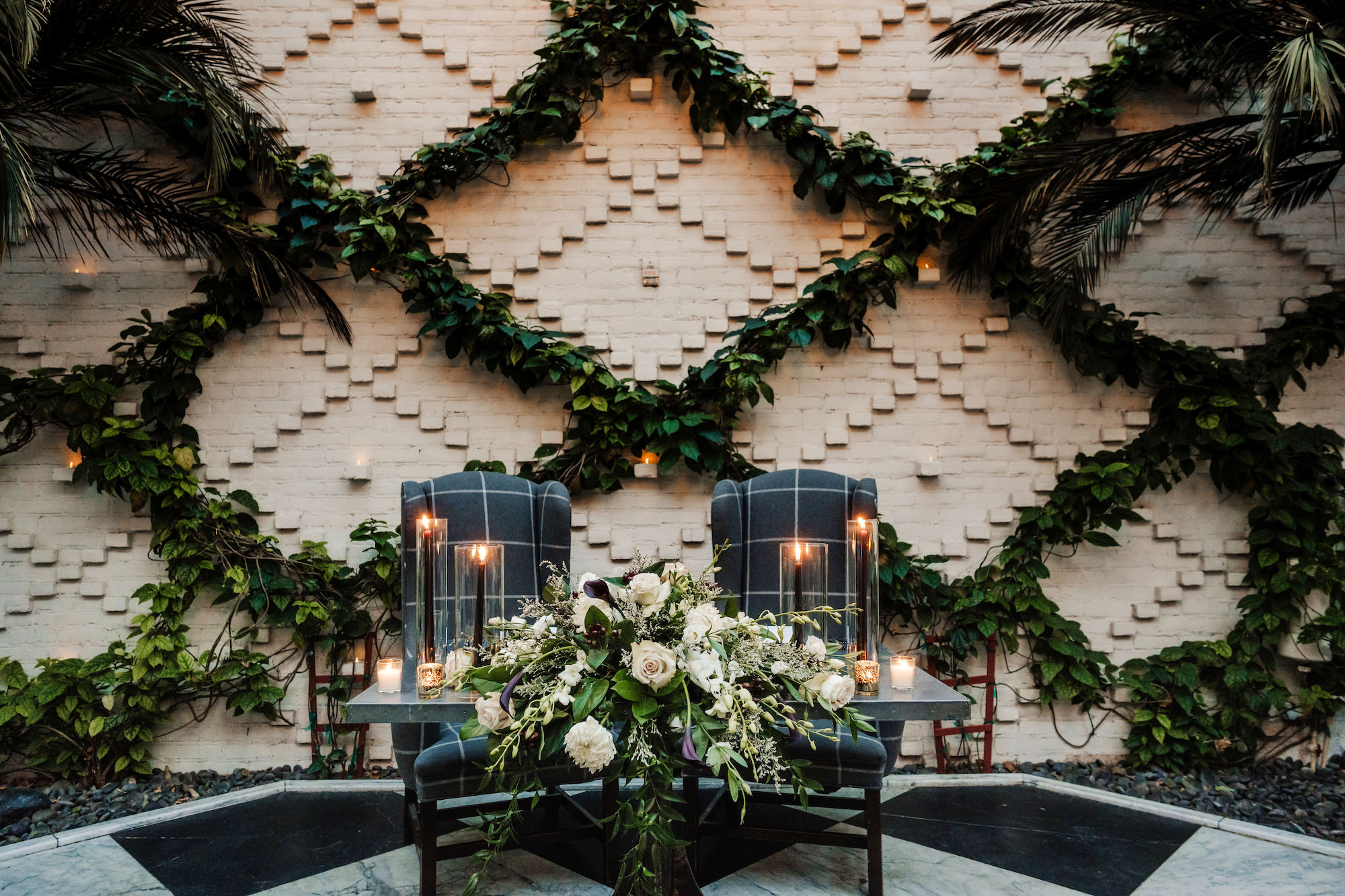 Sweetheart Table with Greenery and White Florals, Black Candles and Upholstered Chair Wedding Reception Inspiration