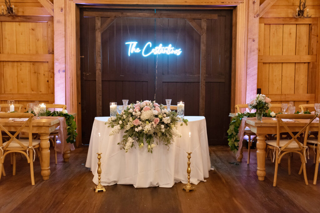 Custom Last Name Neon Sign | Table Top Floral Arrangement with White Hydrangeas, Stock Flowers, Pink Roses, Greenery Ideas | Wooden Crossback Chairs Seating Ideas | Sage Green and Blush Wedding Reception Inspiration