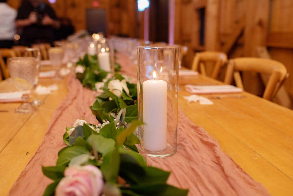 Hurricane Glass Tubes with Pillar Candles Wedding Centerpieces | Greenery, White Baby's Breath, and Pink Roses Garland, Blush Cheese Cloth Table Runner Reception Inspiration