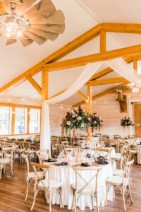 Rustic Crossback Wooden Chairs Seating Inspiration | Tall Flower Stands with Pink Roses, Red Burgundy Carnations, and Greenery | Brooksville Furniture Rental A Chair Affair | Tampa Bay Wedding Venue Legacy Lane Weddings