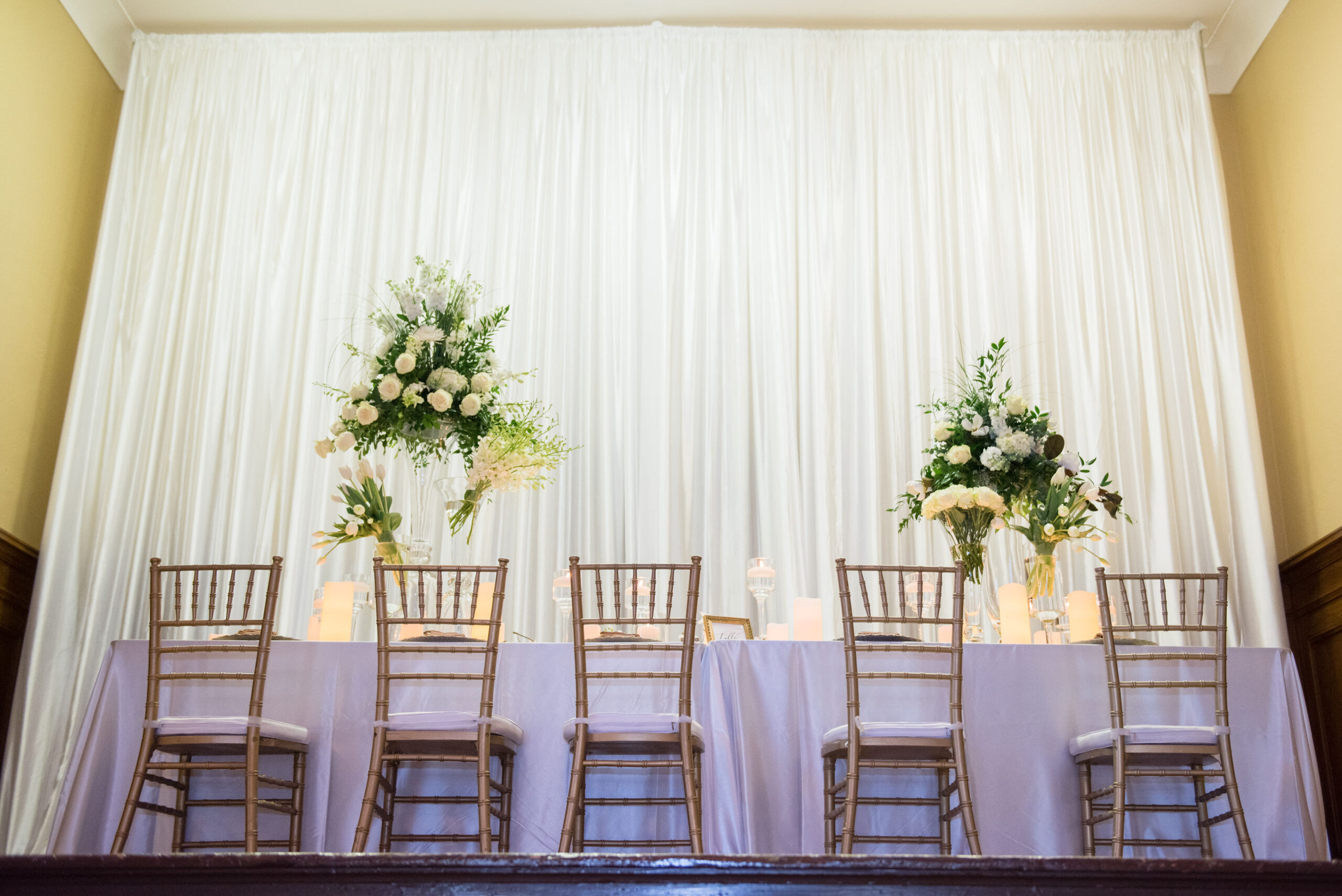 Gold Chaivari Chairs with White Drapping and Tall Centerpieces | Elegant White and Gold Wedding Reception Ideas