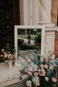 Welcome Wedding Sign Mirror in Picture Frame Surrounded by Muted Pastel Florals Wedding Decor