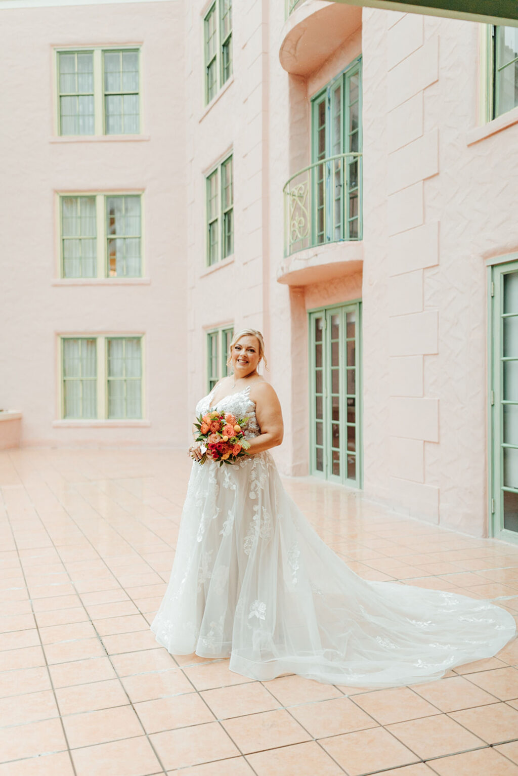 Bride with Updo and Soft Glam Ideas Posing in Bridal Ballgown with Bright Floral Bouquet for Bridal Portrait | St Pete Florida Hair and Makeup Femme Akoi
