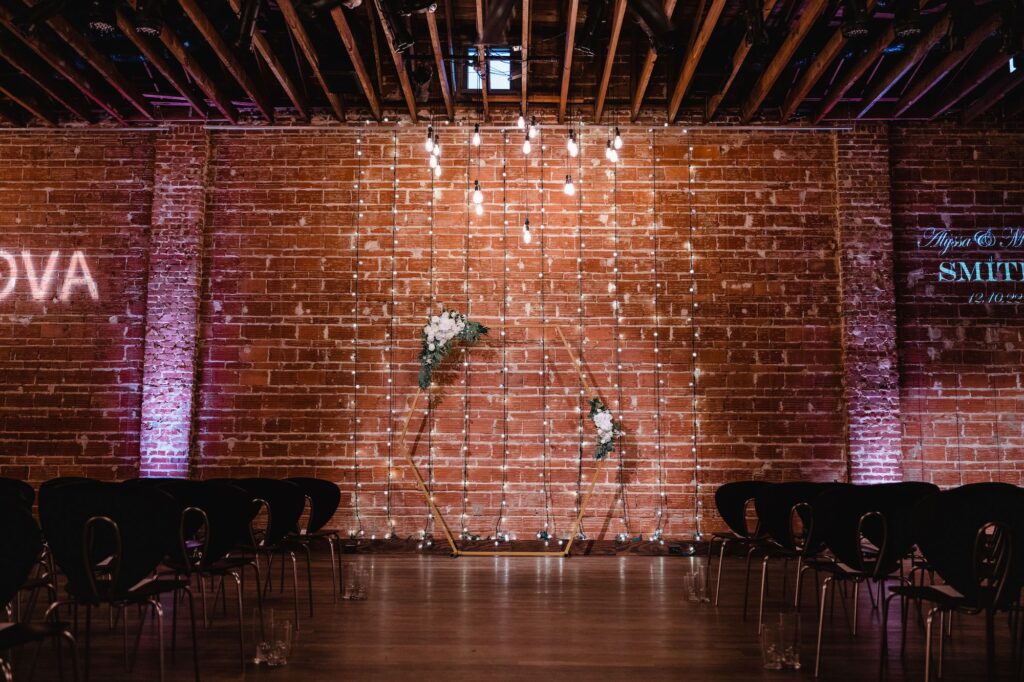 Industrial Style Wedding Ceremony with Black Seating and Gold Circle Arch with White Floral and Greenery Detail Inspiration | St. Petersburg Wedding Venue NOVA 535