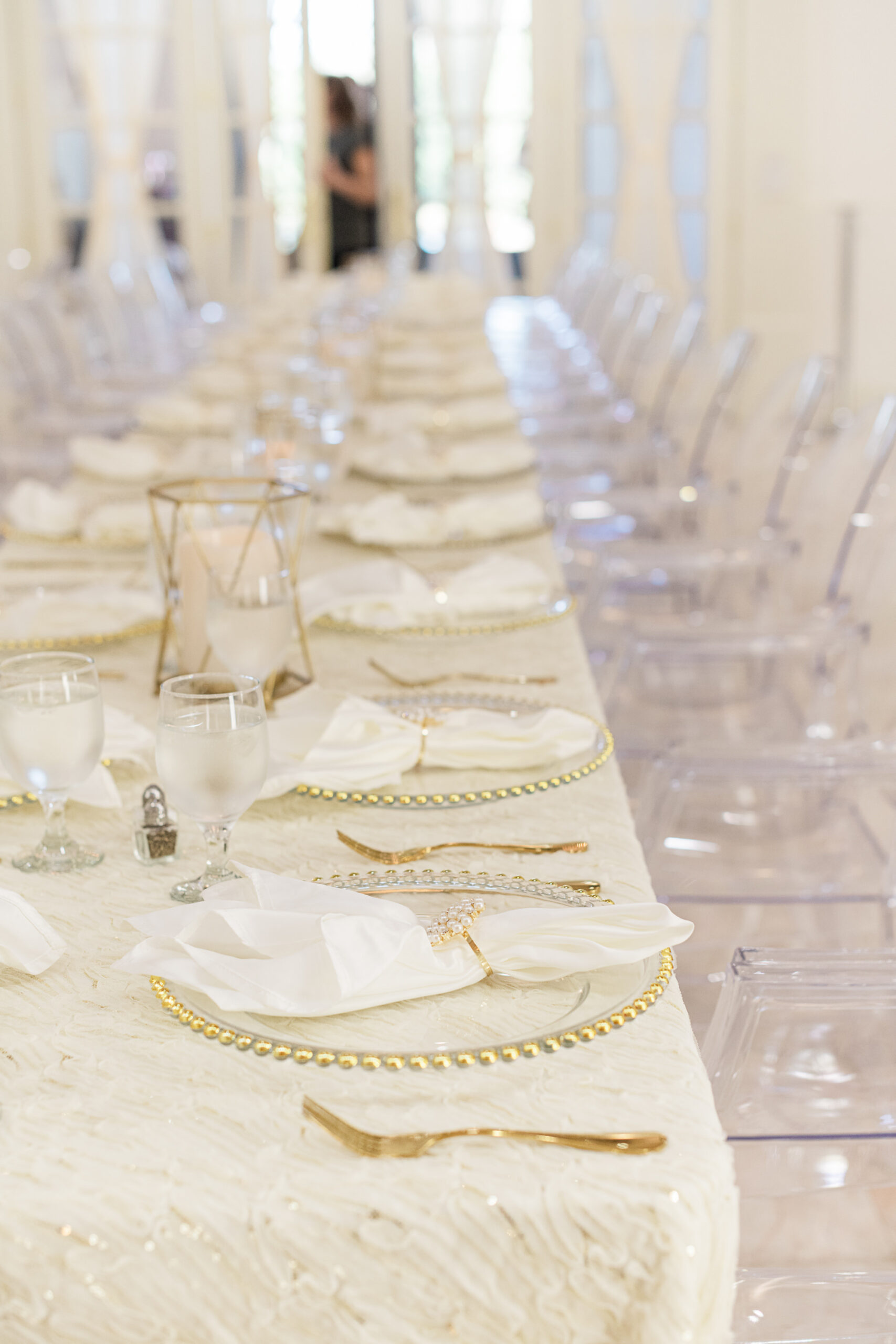 Elegant Long Feasting Tables with White Linens and Ghost Chairs Decor Inspiration | Gold Beveled Glass Chargers and Geometric Votives | Pearl Napkin Rings | Tampa Bay Outside the Box Rentals | Wedding Venue Whitehurst Gallery