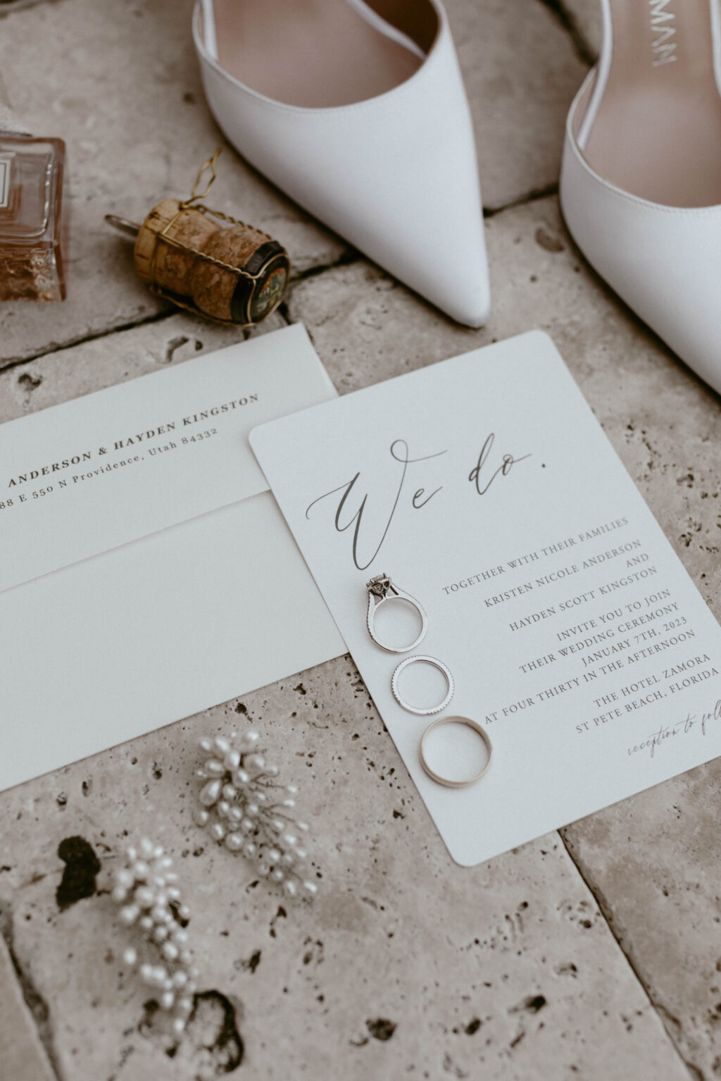 Classic White Cursive Wedding Invitation Flatlay with Wedding Bands and Engagement Ring Inspiration