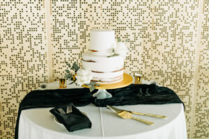 Round Two-tiered Semi-Naked Wedding Cake with Floral Accents | Black, White, and Gold Cake Table Ideas