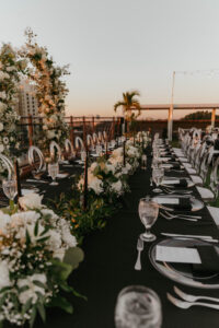 Infinity Ghost Chairs with Silver Flatware and Black Linen with White Florals and Greenery Reception Inspiration | St. Petersburg Outside the Box Rental Linens | Florist Lemon Drops Weddings & Events