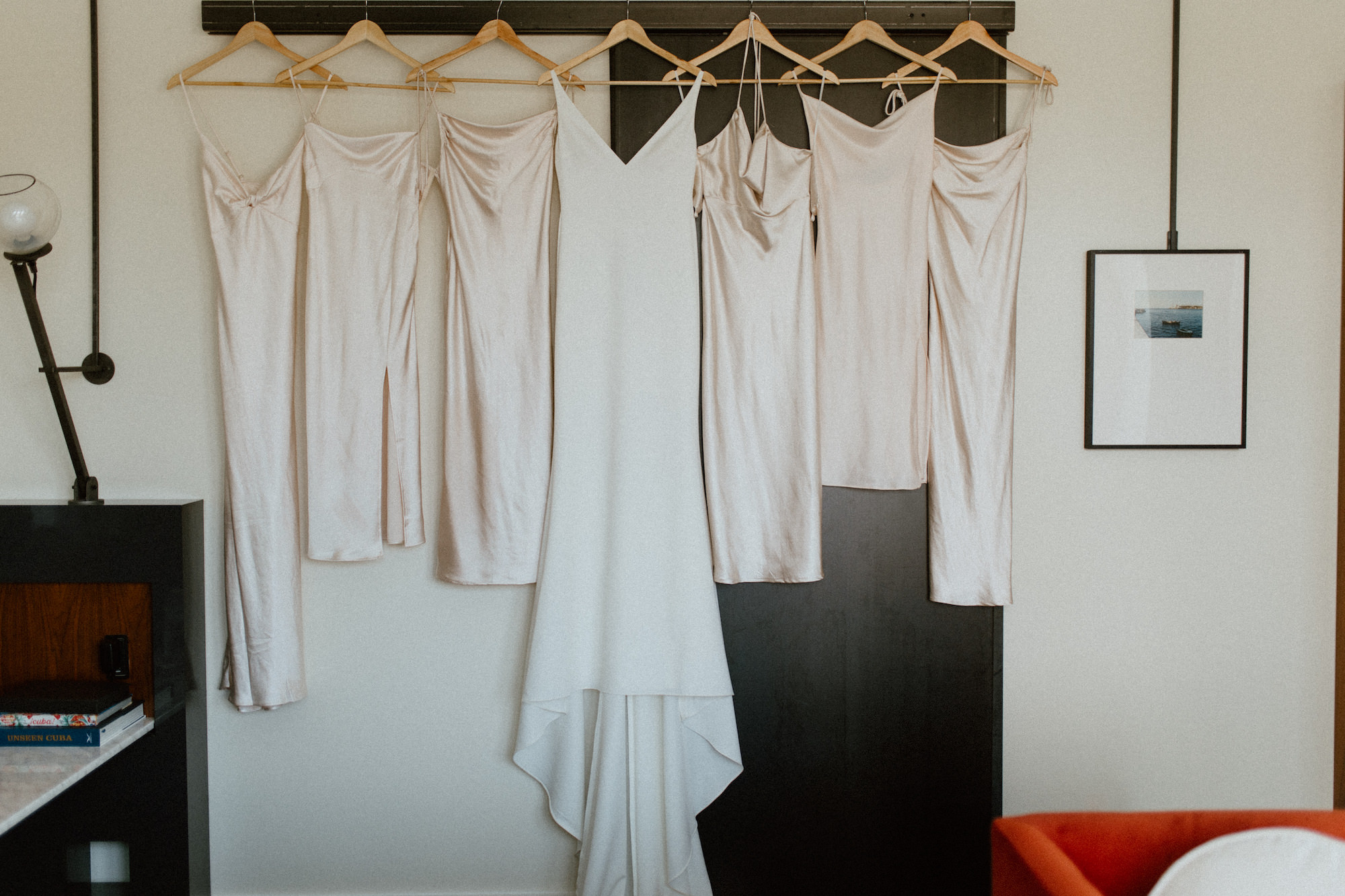 White Satin Simple Classic Made With Love Bridal Wedding Dress on Hanger with Cream Midi Bridesmaids Dress Ideas Hanging Portrait