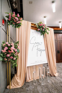Large Welcome Ceremony Sign with Peach Drapery, Floating Candles | Pink Roses with Eucalyptus Floral Arrangements