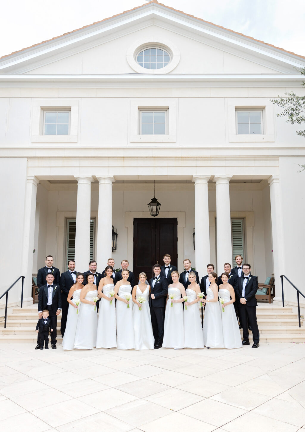 Groom and Groomsman Black Tuxedo Classic Wedding Attire Inspiration | All-White Amsale Bella Bridesmaids Strapless Dress Ideas with Classic Cala Lily Bouquets