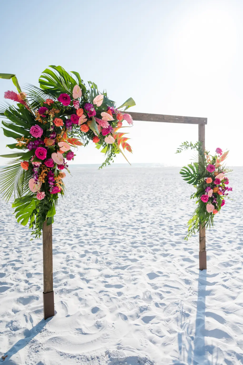 Wooden Tropical Inspired Ceremony Arch with Monstera Leaves and Pink and Orange Florals Ideas | Sarasota Florist Save the Date Florida