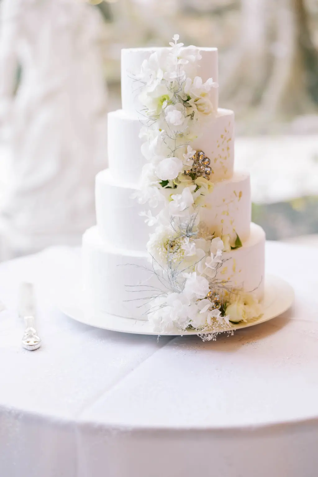 Round Four-tiered Wedding Cake with Gold Foil and White Flower Accents Inspiration