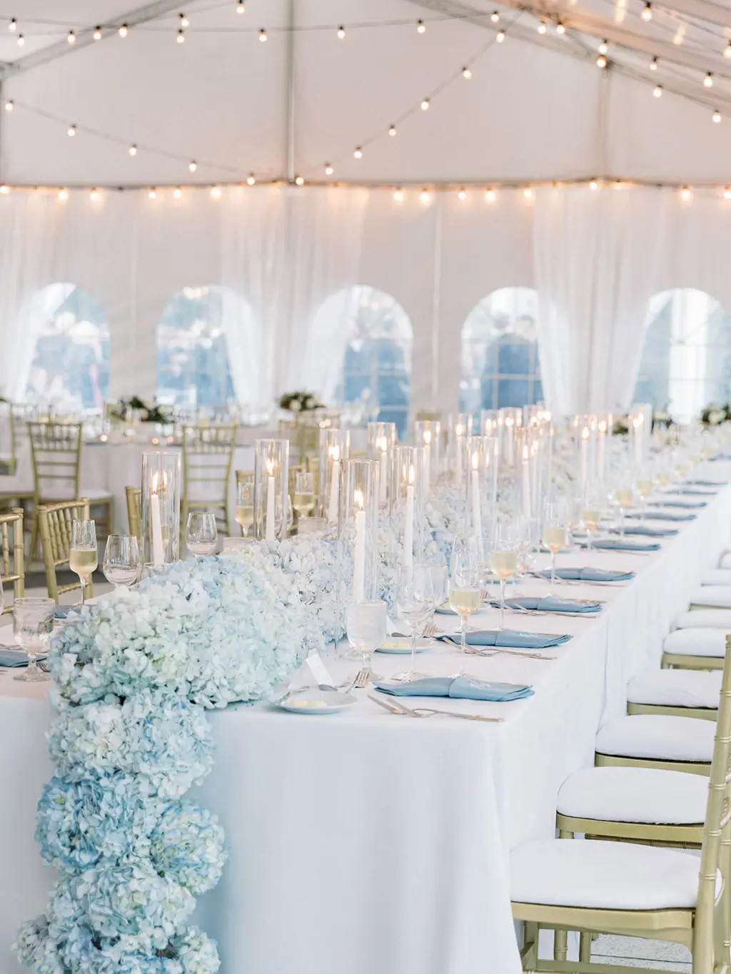 Classic Blue and White Hydrangea Garland Centerpiece with Taper Candles Inside Hurricane Glass Tube for Feasting Table | Classic Blue and White Tented Wedding Reception Inspiration | Tampa Bay Florist Save The Date Florida | Planner EventFull Weddings