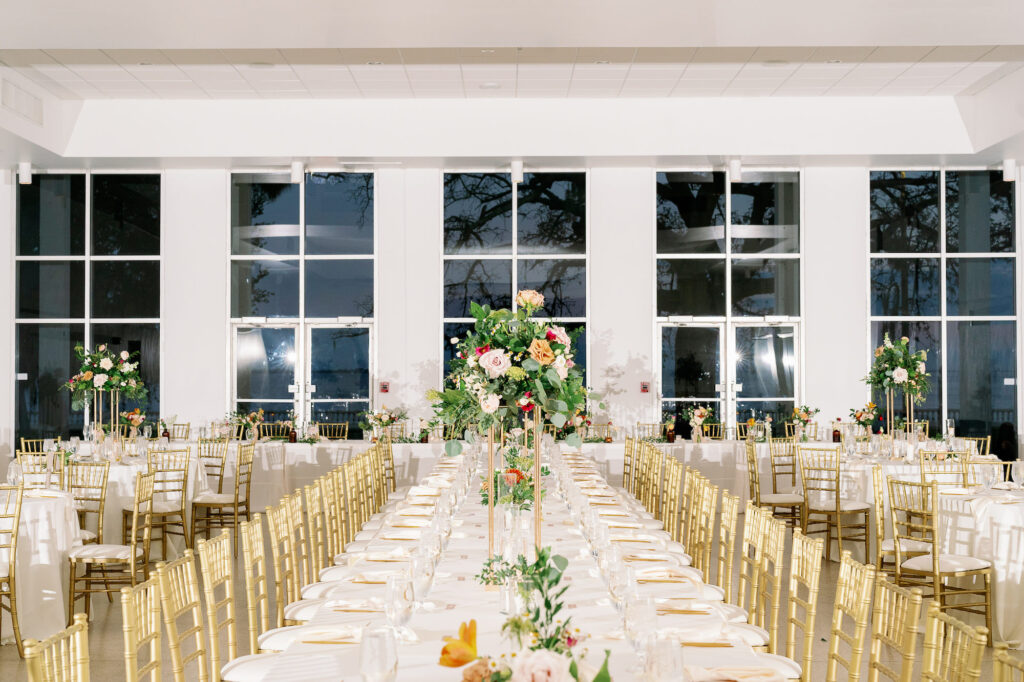 Fall Garden Wedding Reception Inspiration with Long Feasting Tables, Gold Chiavari Chairs and Tall Flower Stands with Greenery and Orange and Blush Roses | Tampa Bay Venue The Tampa Garden Club | Kate Ryan Event Rentals