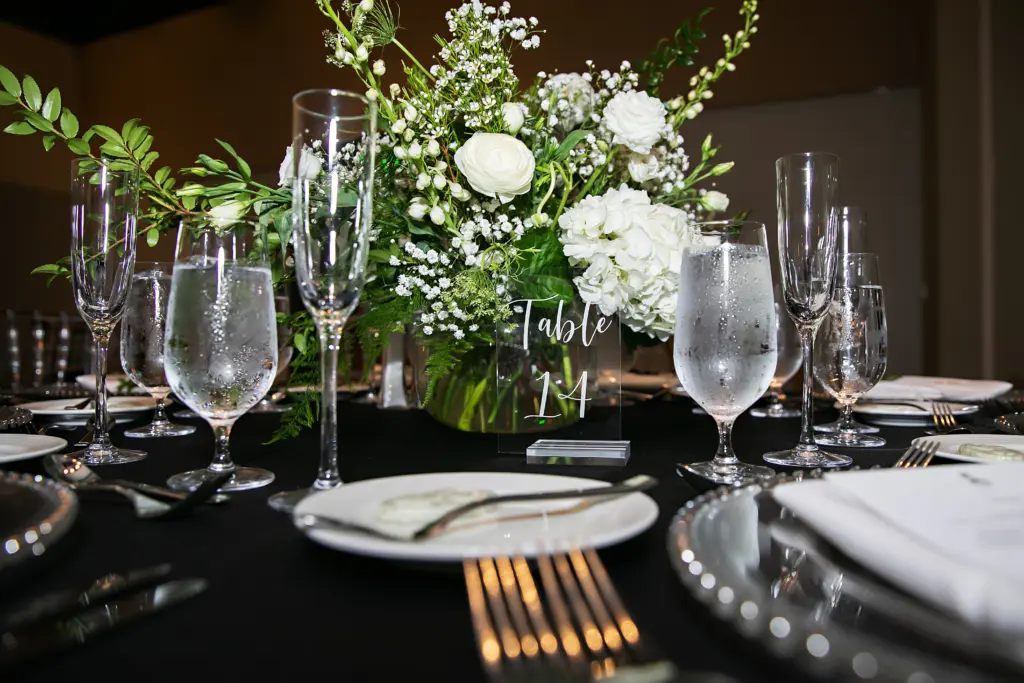 Elegant Black and White Wedding Reception Decor Inspiration | White Snapdragon, Baby's Breath, Roses, and Hydrangea Centerpiece Ideas | Modern Acrylic Table Number Sign