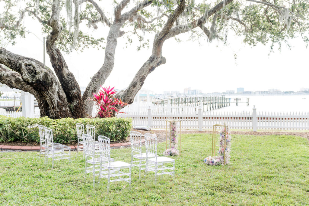 Waterfront Wedding Ceremony Inspiration | Clear Acrylic Chairs | Gold Cascading Flower Stand for Altar Ideas | Sarasota Florist Save The Date Florida | Venue Palmetto Bed and Breakfast