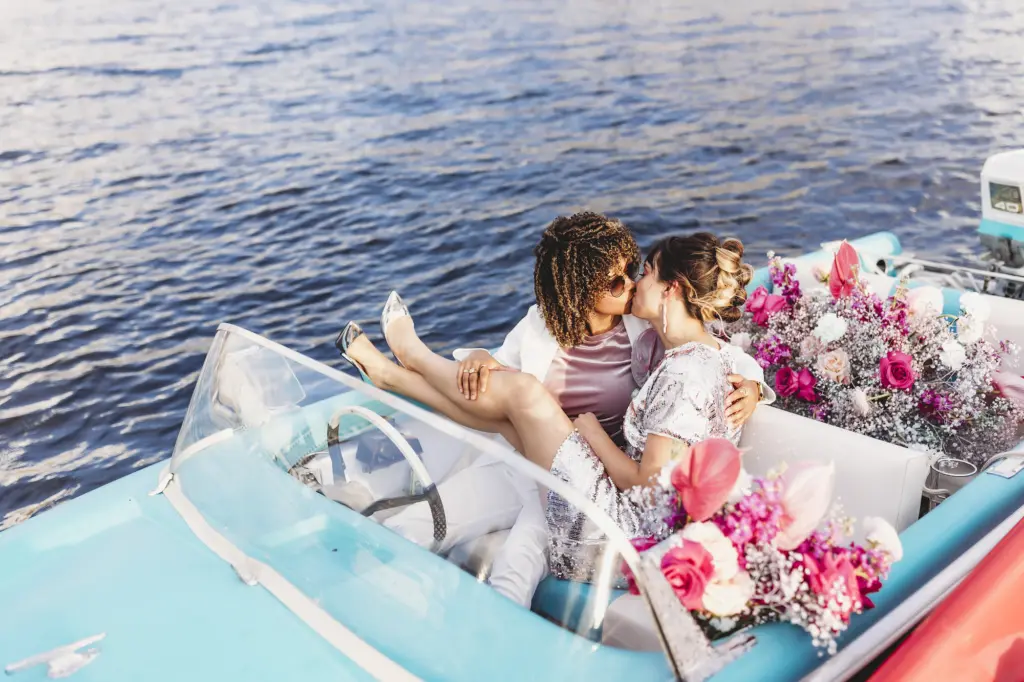 LGBQT+ Couple Kissing on Boat Portrait with Vibrant Pink Floral Inspiration on Hillsborough River | Tampa Wedding Planner Wilder Mind Events